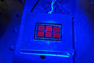 The record-setting solar cell shines red under blue luminescence. Photo by Wayne Hicks, NREL